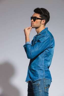 ışık gri arka plan üzerinde duran ve tarafına bakarak gözlüklü ensive casual adam yan görünüm
