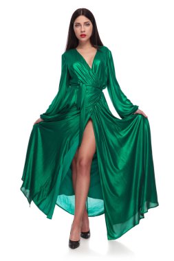 Beyaz arka plan üzerinde cross-legged ayakta iken uzun yeşil elbisesinin tutan zarif kadın