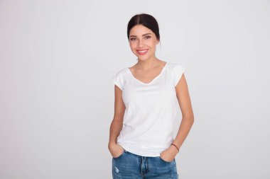 rahat rahat kıyafetler elleri ceplerinde ışık gri arka plan üzerinde duran kızla