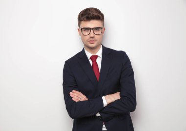 Donanma takım elbise eller hafif gri arka plan üzerinde çarpı işareti ile ayakta emin işadamı portresi