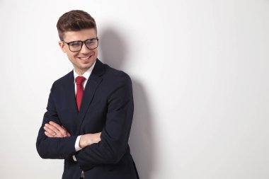 Yan ışık gri arka plan üzerinde dururken isteyen katlanmış ellerle neşeli işadamı portresi