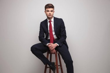 yakışıklı işadamı ellerini tutarken birlikte hafif gri arka plan üzerinde ahşap sandalye üzerinde rahatlatıcı