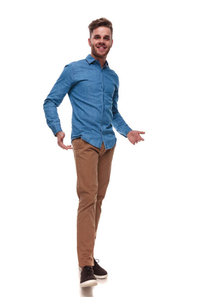 happy casual man wearing a blue shirt standing on white background and presenting, full length picture