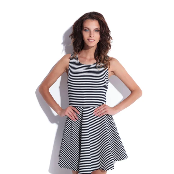 gülümseyen şirin sundress holding giymiş seksi kadın kalçaları dururken yakınındaki bir beyaz duvar, portre resim