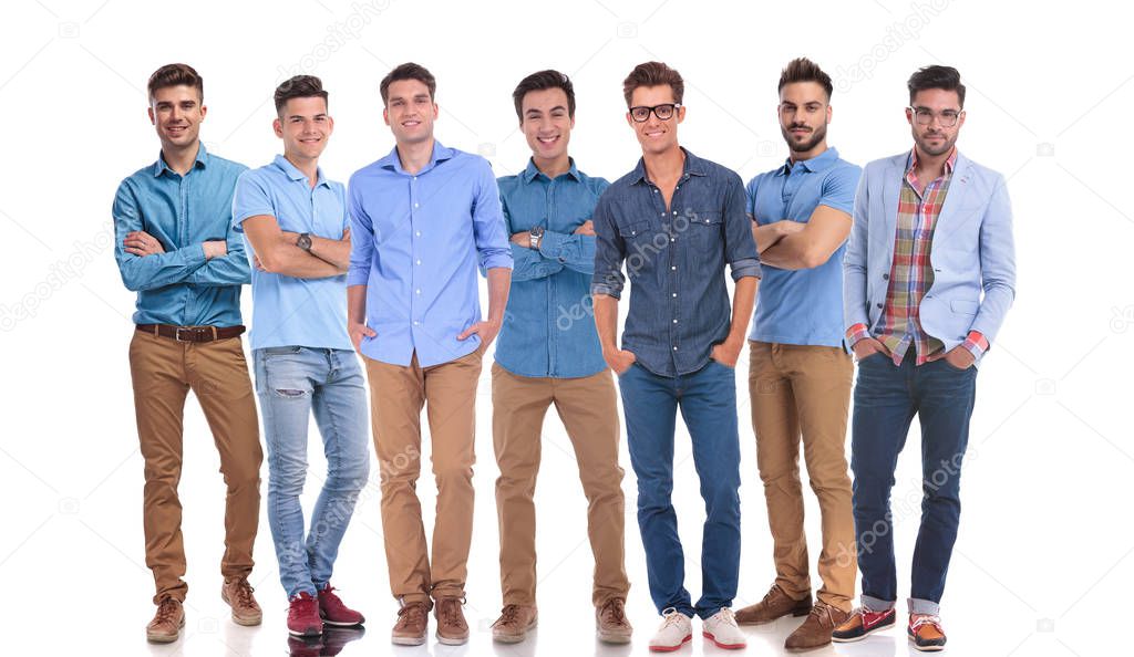 work group of seven hapy casual men standing on white background with hands in pockets or folded hands, looking confident and relaxed