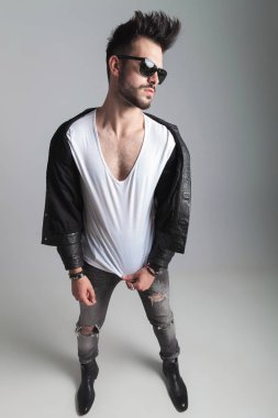 güneş gözlüğü ve yan deri ceket gibi geldi ise onun beyaz t-shirt holding ve beyaz arka plan, tam uzunlukta resim üzerinde duran adam