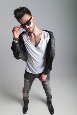 adam giyen deri ceket ve gri kot giderir duran güneş gözlüklerini açık gri renkli, tam uzunlukta resim