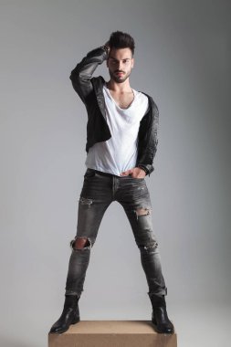 deri ceket cebinde, tam boy resmi bir el ile bir ahşap kutu üzerinde duran saçları sabitleme yakışıklı adam