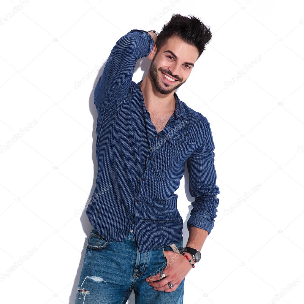 smiling and seductive man in navy Guess shirt posing while standing on white background