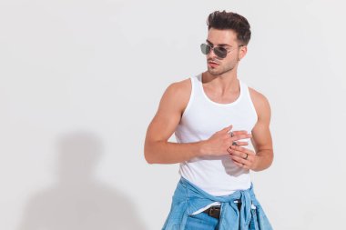 casual adam fanila ve güneş gözlüğü takmış yüzük giderir ve yan spot, portre resim içinde beyaz arka plan üzerinde dururken görünüyor