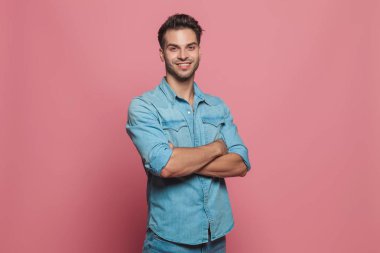 katlanmış ve pembe arka plan gülümseyerek el ile ayakta emin casual adam portresi