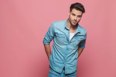 Onun geri kırmızı arka plan üzerinde duran arkasında el ile kot gömlek giyen baştan çıkarıcı adam portresi