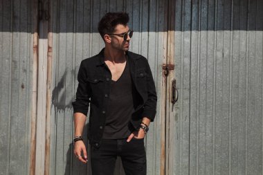 güneşli bir günde bir metal duvar yakınındaki dışında dururken yan isteyen gözlüklü rahat adam portresi