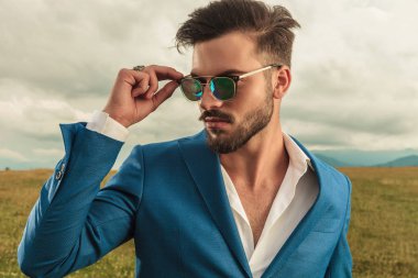 güneş gözlüğü sabitleme ve yan duran dışında bir çim alandaki isteyen mavi takım elbise giymiş yakışıklı adam portresi