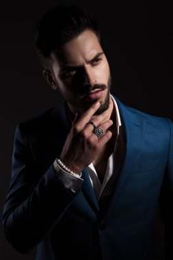 mavi bir takım elbise giyen dalgın akıllı casual adam siyah arka plan üzerinde duran ve yan için arıyorum