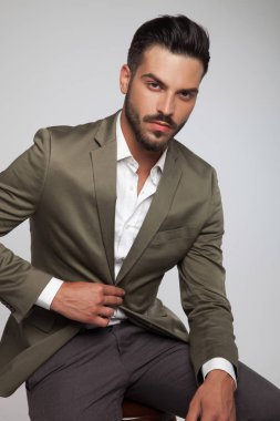 ışık gri arka plan üzerinde yeşil bir takım elbise giymiş oturmuş yakışıklı adam portresi