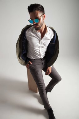 yeşil elbise rahatlatıcı ahşap sandık üzerinde çekici şık erkekte cep, açık gri renkli bir el ile