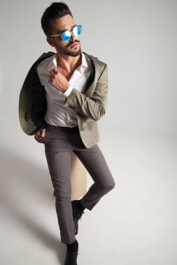 tarafa, açık gri renkli seyir sırasında bir ahşap kutu üzerinde oturan yeşil takım elbise rahat şık adam