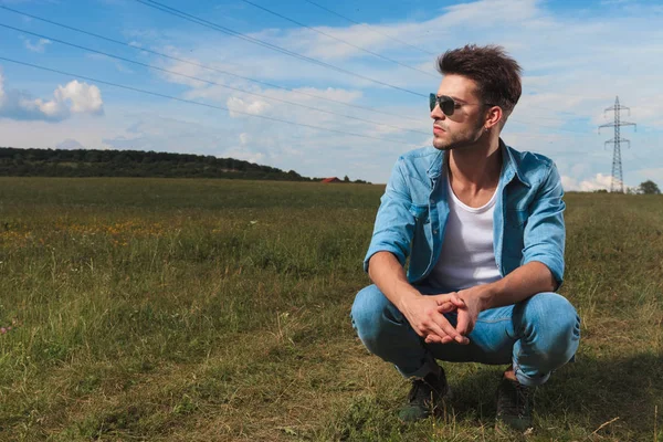 Casual Man Met Zonnebril Gehurkt Een Grasveld Een Het Platteland — Stockfoto