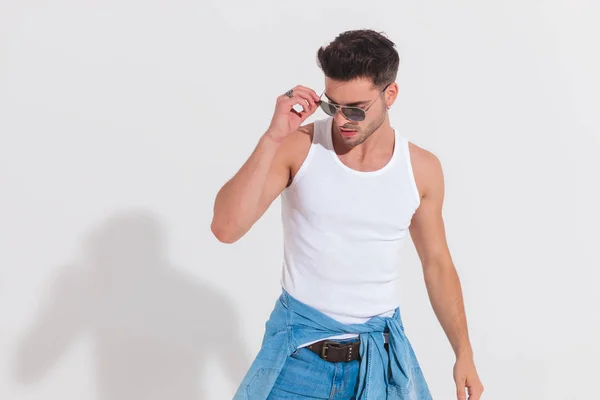 Casual Man Studio Light Fixes Sunglasses Looks Side While Standing — Stock Photo, Image