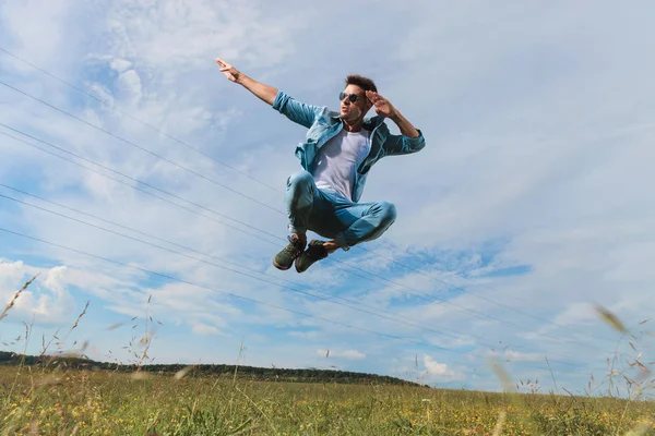Young Man Sunglasses Salutes His Hands Side Whle Jumping Grass — Stock Photo, Image