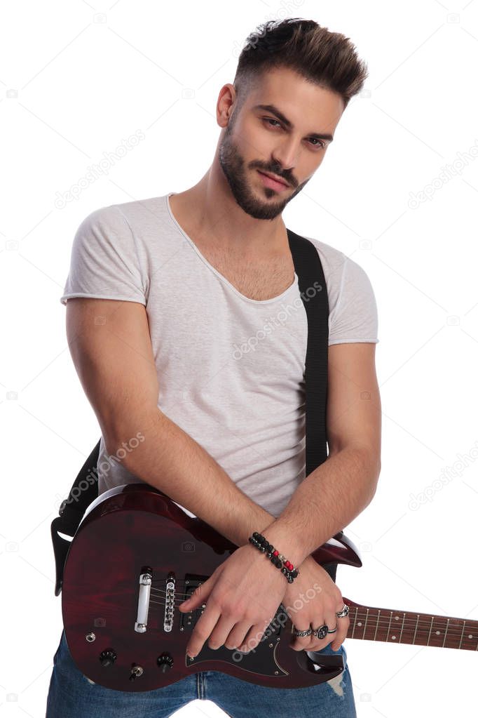 portrait of handsome casual man holding his electric guitar while standing on white background