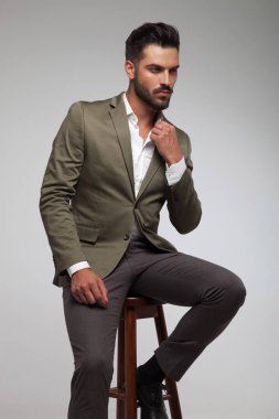 zarif genç adam açık gri renkli tahta sandalyede oturur ve tarafına görünüyor