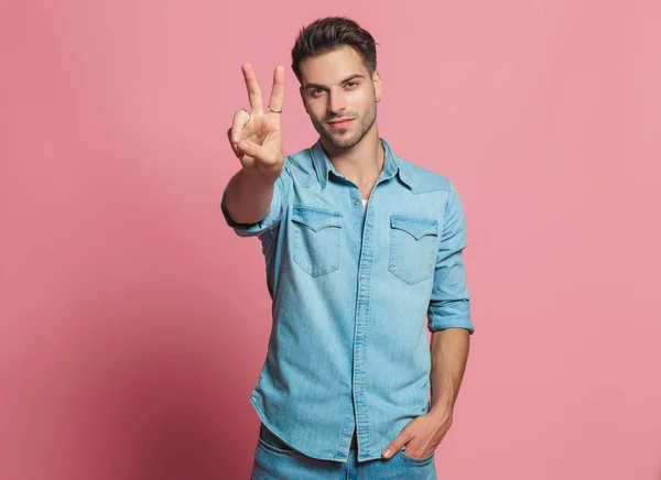 Casual Man Makes Peace Sign While Holding His Pocket Standing — Stock Photo, Image
