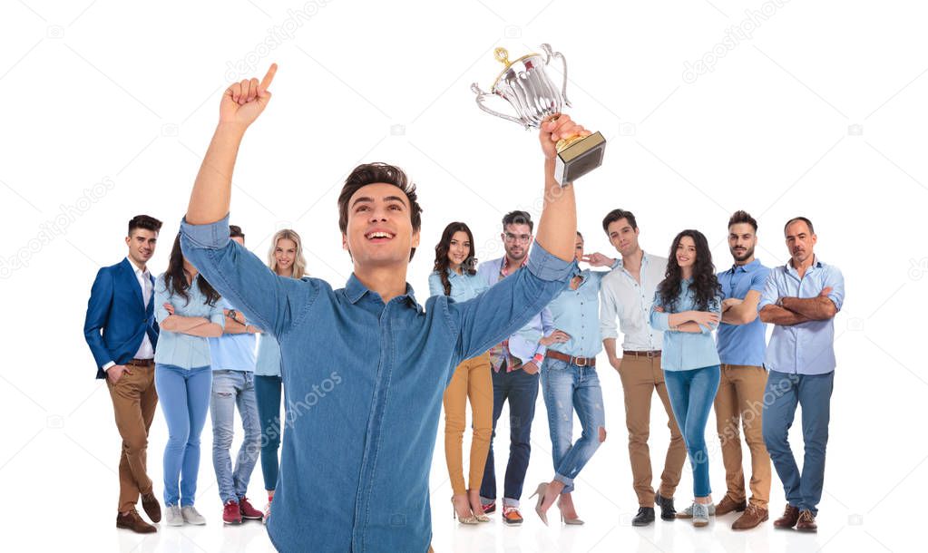 successful casual team with young leader celebrating in front while holding a trophy and a hand in the air
