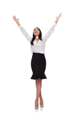 happy businesswoman celebrates and looks up while standing cross-legged on white background clipart