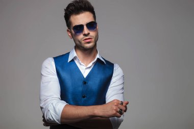 ışık gri arka plan üzerinde katlanmış ve tarafına bakarak elleri olan bir mavi Jile ayakta giyen genç adam portresi