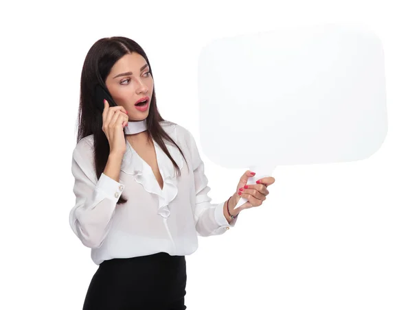 Zszokowana Kobieta Trzymając Telefon Mowy Bańka Patrząc Bok Stojąc Białym — Zdjęcie stockowe