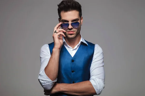 Retrato Del Hombre Elegante Fijando Sus Gafas Sol Azules Mientras —  Fotos de Stock