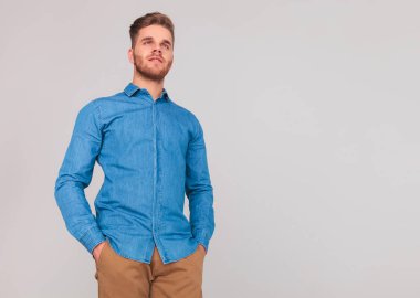 Açık gri renkli tarafa bakarken ceplerinde portre çekici adam ile ayakta eller