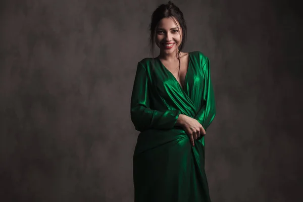 Усміхнена Брюнетка Жінка Покриває Себе Зеленню Сукні Стоячи Сірому Фоні — стокове фото