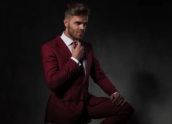 Caballero Traje Fijando Corbata Roja Mirando Lado Mientras Está Sentado — Foto de Stock