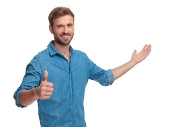 sunulması ve beyaz arka plan üzerinde ok işareti yaparak genç casual adam gülümseyen