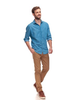 bir genç casual adam yürüme ve uzak beyaz arka plan üzerinde seyir yan görünüm