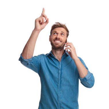 phne üzerinde genç mutlu casual adam beyaz zemin üzerine işaret ediyor