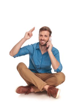 mutlu oturma rahat adam telefonda konuşuyor ve herkes için alnına parmaklarıyla askeri bir selam ile beyaz arka plan üzerinde selamlıyor