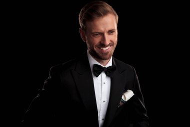 aşağıya bakar kameranın siyah arka plan üzerine uzak smokin ve papyon genç adam gülüyor