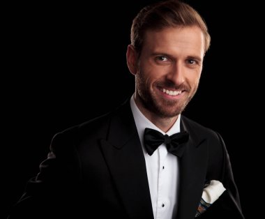 Smokin siyah stüdyo arka plan üzerinde gülümseyen bir zarif adam portresi