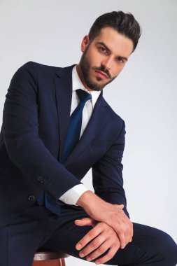 Donanma takım açık gri renkli dizinde üzerinde dirseğini dinlenme oturmuş kurumsal adam portresi