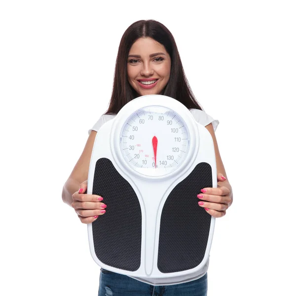 体重計を持って 白い背景の上に立っている間笑顔ブルネットの女性の肖像画 — ストック写真