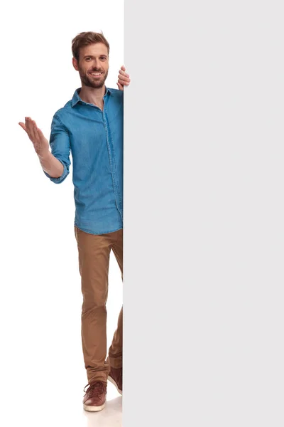 Молодой Улыбающийся Случайный Мужчина Представляет Чистый Рекламный Щит Приветствует Белом — стоковое фото