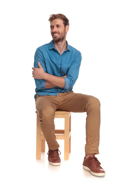 Sorridente Sentado Jovem Casual Homem Olha Para Lado Fundo Branco — Fotografia de Stock