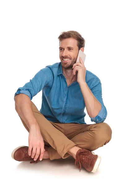 Casual Glimlachende Man Zittend Vloer Praten Telefoon Kijkt Naar Kant — Stockfoto