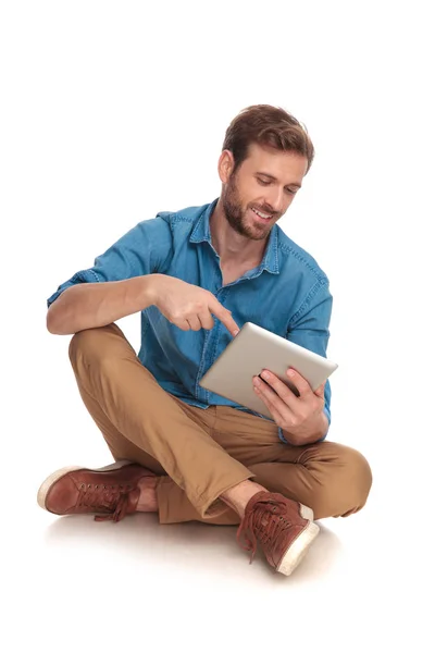 微笑坐在不经意的男人触摸他的平板电脑屏幕上 工作的白色背景 — 图库照片