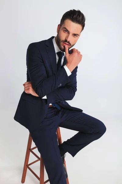 Portret Seksowny Biznesmen Siedzi Stołku Dotykając Ustami Jasnoszarym Tle — Zdjęcie stockowe
