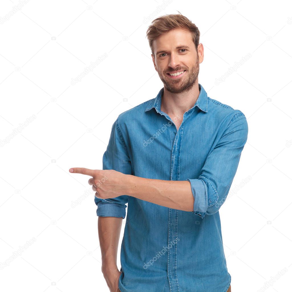 young casual studnt points finger to side on white background